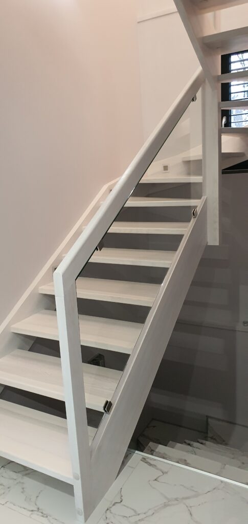 Schody policzkowe – jesion bielony. Balustrada wypełniona szkłem. Realizacja Jankowice