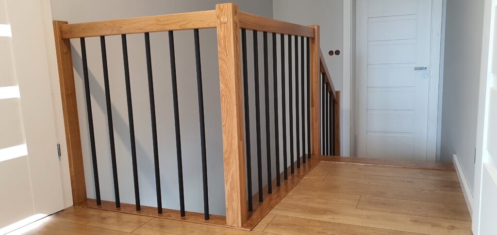 Schody dąb natura, podstopnice malowane na biało, balustrada z czarnymi rurkami. Realizacje w Żorach